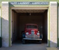 an old red truck is sitting in a garage under a sign