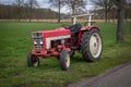 Old red vintage tractor on the side of the road, used by farmers Royalty Free Stock Photo