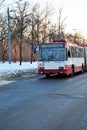Old red and white trolley moving along snowy park, winter