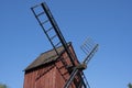 And old red windmill with wooden blades against a bright blue sky Royalty Free Stock Photo