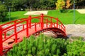 Old red wooden bridge across small river in a green park. Vintage Japanese style bridge above the water. Uman, Ukraine in summer, Royalty Free Stock Photo