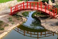 Old red wooden bridge across small river in a green park. Vintage Japanese style bridge is reflected in the water. Uman, Ukraine Royalty Free Stock Photo