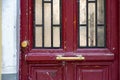 Old red wooden door details closeup. Cracked stucco wall and shabby surface of distressed painted wood panel with dirty window Royalty Free Stock Photo