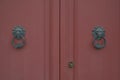 Old red wooden door with metallic ancient door handles and knocker in the lion shape close-up. Exterior design. Building exterior Royalty Free Stock Photo