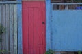 Old red wooden door near a blue metal gate Royalty Free Stock Photo