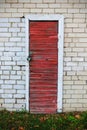 Old red wooden plank door with a lock in white brick wall Royalty Free Stock Photo