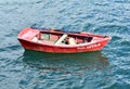 Old red wooden rowboat floating on the sea. Camelle, Rias Baixas, Galicia, Spain.