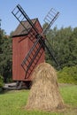 Old red wooden windmill with a haystack in the foreground. Finnish agriculture Royalty Free Stock Photo