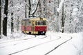 Old red yellow tram rides through the snowy forest.