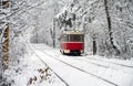 Old red yellow tram rides through the snowy forest. Winter plot.