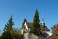 Old reformed church building in Urdorf, Switzerland among trees, lateral view with detail of the church tower Royalty Free Stock Photo