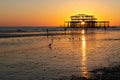 The old remains of Brighton Pier left standing in sea with beautiful waves and seagulls on the beach. Royalty Free Stock Photo