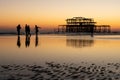 The old remains of Brighton Pier left standing in sea with beautiful waves, seagulls and local people on the beach. Royalty Free Stock Photo