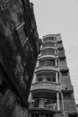 Old residential building still standing against newly developed urban residential flats, contrasty black and white image. Howrah,