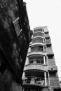 Old residential building still standing against newly developed urban residential flats, contrasty black and white image. Howrah,