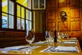 Old restaurant with wooden walls, prepared table with wineglasses.