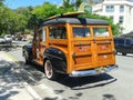 Old restored wood panelled American wagon as surf woody with board on top in street