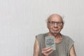 Old retired man not combed in gray shirt is holding savings book Checkbook in his hand.