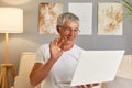 Old retired man waving hand talking to webcam make distant video call chat on laptop whiloe sitting on sofa, cheerful grandpa Royalty Free Stock Photo