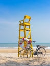 Old retro black bicycle with flowers bouquet beside Life ring for life safety on yellow lifeguard stand station or lifeguard chair Royalty Free Stock Photo