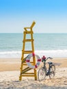 Old retro black bicycle with flowers bouquet beside Life ring for life safety on yellow lifeguard stand station or lifeguard chair Royalty Free Stock Photo