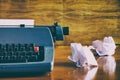 Old retro blue typewriter on a wooden desk with crumpled papers