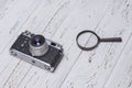 Old retro camera and magnifying glass on white boards Royalty Free Stock Photo