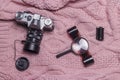 An old retro camera, photographic film and a magnifying glass lie on a pink wool sweater