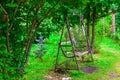 An Old Retro Iron Wrought Metal Swing With A Wooden Bench In A Vintage Style Stands In A Garden Or Park For Children`s