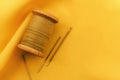 Old retro sewing accessories lie on a yellow fabric. Needle and thread Royalty Free Stock Photo