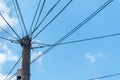 Old retro style wooden pole with many electric supply wires or cables against blue sky Royalty Free Stock Photo