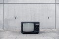 Old retro tv stand outside on street in front of grungy concrete wall without signal on screen only noise Royalty Free Stock Photo