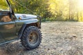 Old retro vintage 4x4 convertible suv vehicle on dirt gravel unpaved road in summer at sunset morning sun. Off road car Royalty Free Stock Photo