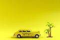 Old retro yellow toy car taxi and toy palm on yellow background with copy space. Travel concept Royalty Free Stock Photo