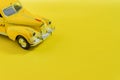 Old retro yellow toy car taxi on yellow background with copy space. Selective focus, Travel concept Royalty Free Stock Photo