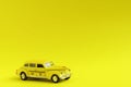 Old retro yellow toy car taxi on yellow background with copy space. Travel concept Royalty Free Stock Photo
