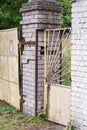 Old rickety rusty gate and metal yellow wicket with a lock between the two brick pillars Royalty Free Stock Photo