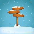 Old rickety wooden signpost covered with snow on the snowy ground. Three arrow shaped planks pointing in different directions.