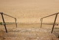 Old rickety worn stone steps leading with handrails leading down to sandy beach