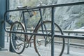 Old road bike attached to the fence next to the highway.