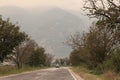 Old road, empty, no cars, only one car in the distance on the road, mountains in the background, trees on the sides of the road