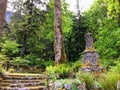 An old rocky staircase covered in moss and interesting stone spire leading through a old growth evergreen forest