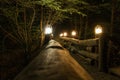 Old romantic wooden bridge over the stream, lit lanterns in the night. Royalty Free Stock Photo