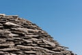 Old roof with grey stone tiles and clear blue sky in background Royalty Free Stock Photo