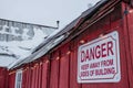 Old roof with snow and danger sign