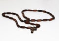 Old rosary with wooden beads laid, christian cross pendant and chain on blurred white background with blank area