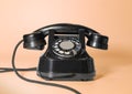 old rotary black telephone with traces of time. on a peach background