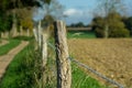 Old rotten fence post & barbed wire. Plowed, seeded agricultural field