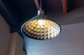 An old round bronze lamp with an electric bulb suspended from the ceiling