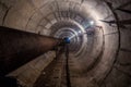 Old round dirty underground technical tunnel of heating duct with rusty pipeline Royalty Free Stock Photo